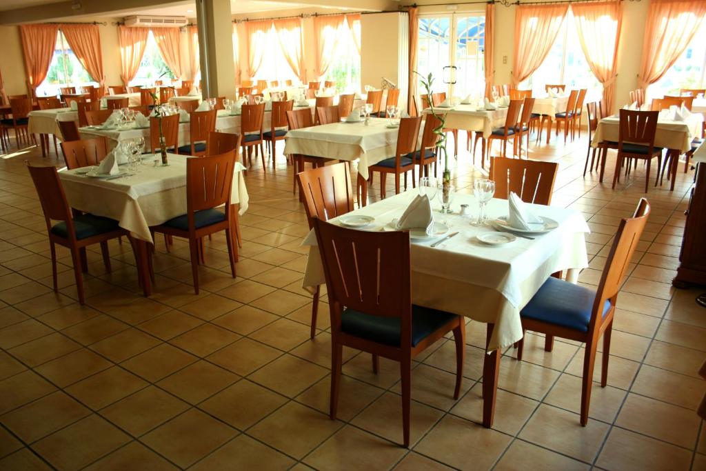 a dining room with tables and chairs and windows at Hotel Ayamontino in Punta Umbría
