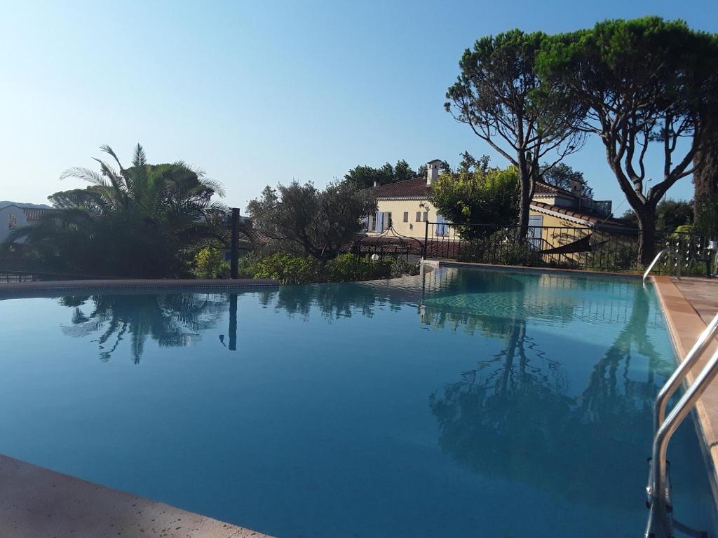 una gran piscina de agua azul con árboles y una casa en Mas Aurélia B&B, en Fréjus