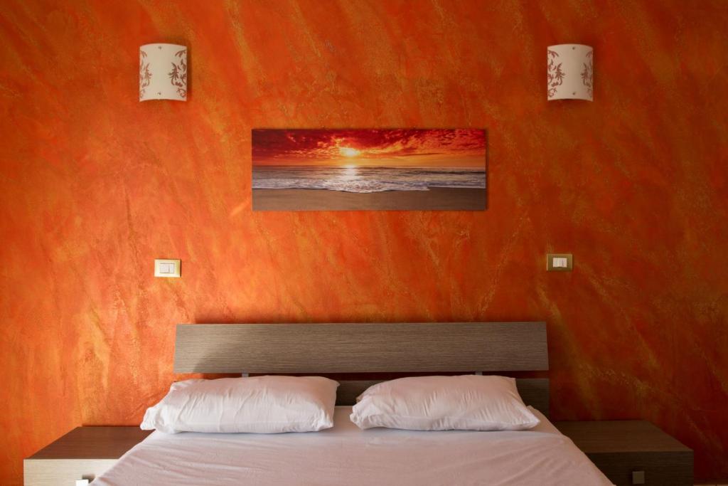 um quarto com uma parede laranja e uma cama com 2 almofadas em Madogi em SantʼAngelo di Brolo