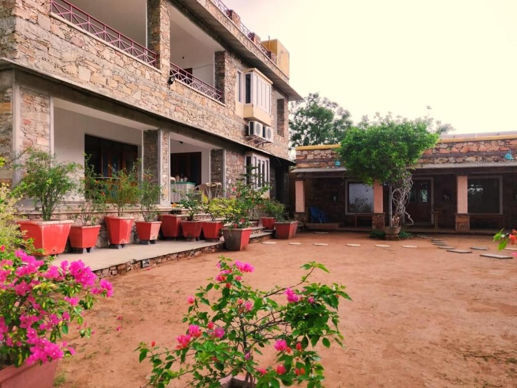 un patio de un edificio antiguo con flores rosas en Devra Udaipur, en Udaipur