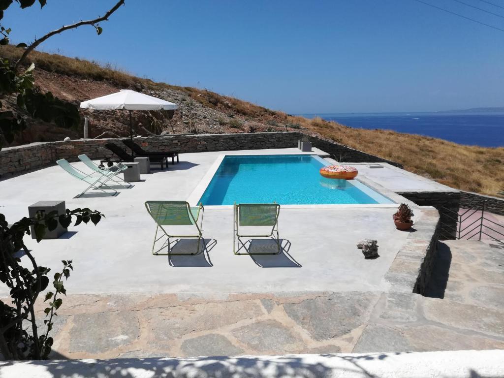 una piscina con 2 sillas de césped y el océano en Villa with Swimming Pool, en Korissia