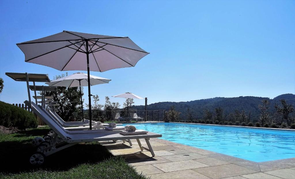 einen Stuhl mit Sonnenschirm neben einem Pool in der Unterkunft Il Poggetto in Greve in Chianti