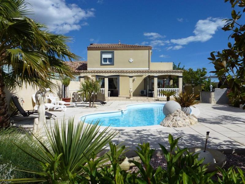 uma casa com piscina em frente a uma casa em Villa Manet Portiragnes em Portiragnes