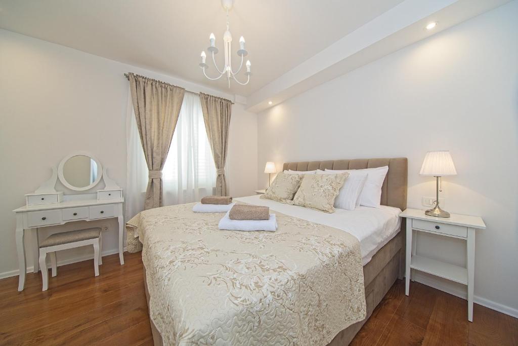 a white bedroom with a bed and a mirror at Apartment Marangun in Ston