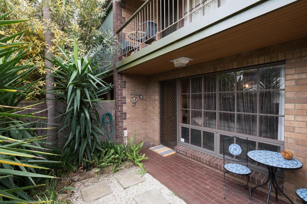 een patio met 2 stoelen en een tafel voor een gebouw bij Glenelg North " Home Away From Home" in Adelaide