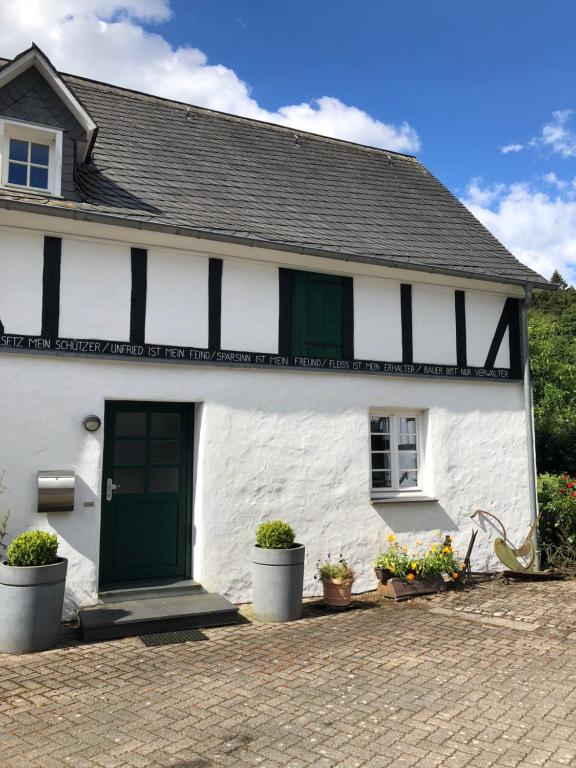 a white and green house with a green door at Ferienwohnung Schulten Hof in Schmallenberg