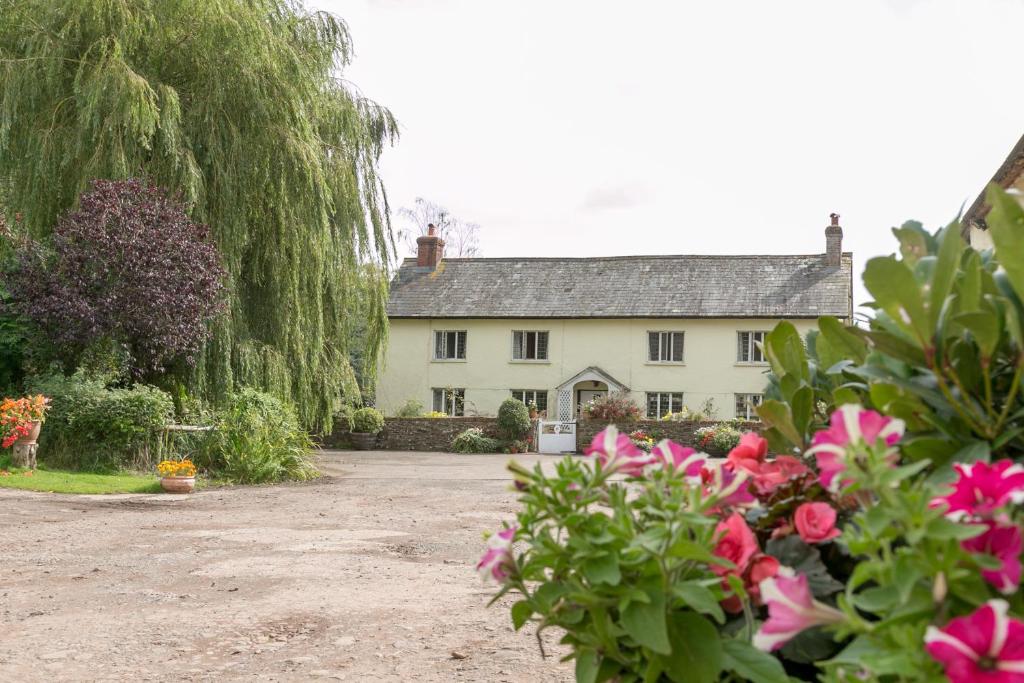 a large white house with flowers in front of it at Lower Ford Farm in Cullompton