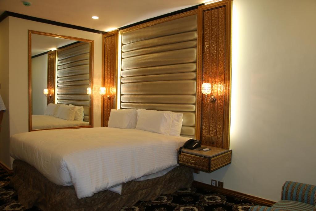 a bedroom with a large bed and a mirror at Indus Hotel in Hyderabad