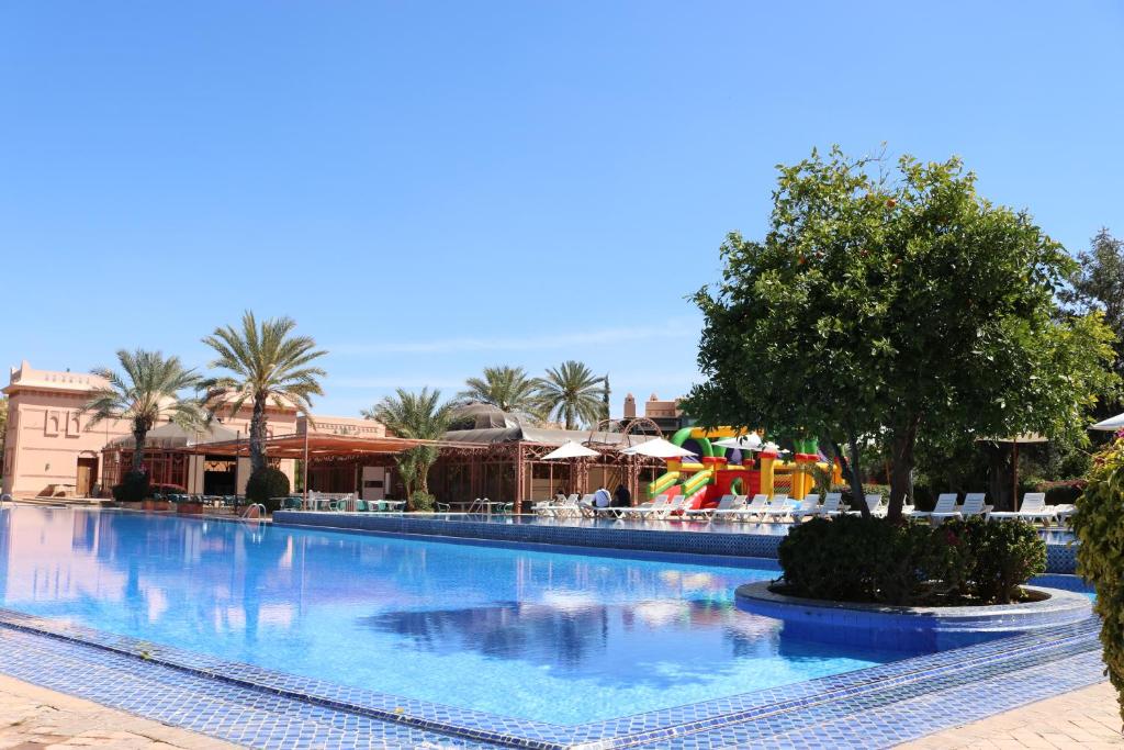 a large swimming pool at a resort with palm trees at Palmeraie village in Marrakech