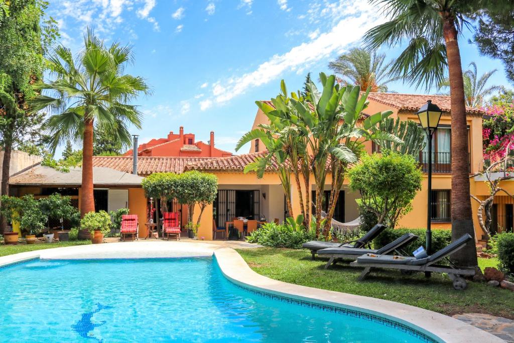 una piscina frente a una casa con palmeras en Villa El Mirador, en Marbella