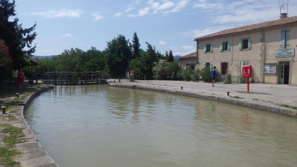 a river in front of a building next to a building at La maison de l'écluse in Trèbes