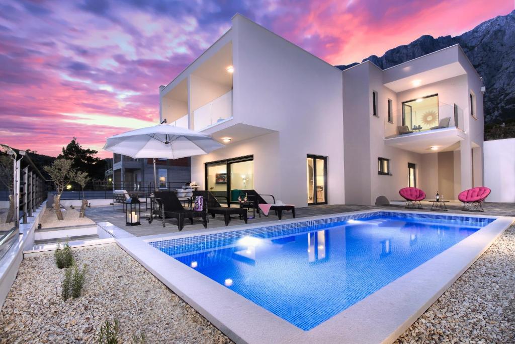 a villa with a swimming pool in front of a house at Villa Navis HEATED POOL in Makarska