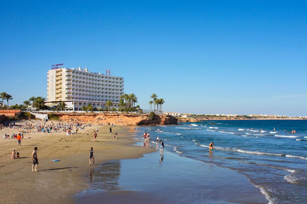 um grupo de pessoas numa praia perto do oceano em Hotel Servigroup La Zenia em Playas de Orihuela