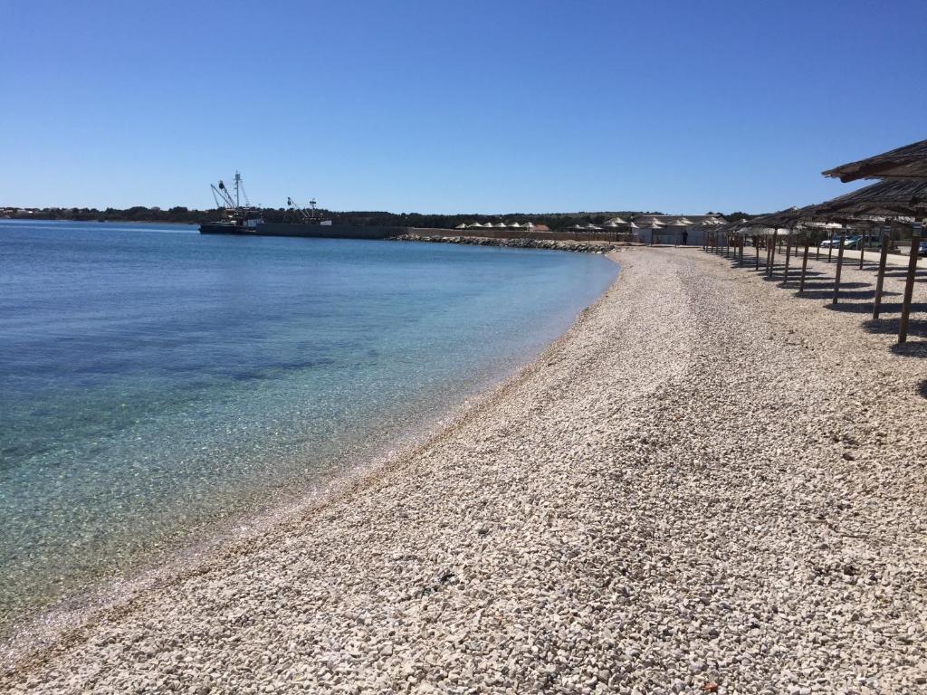 a beach with a rocky shoreline next to the water at Harmony VIR Luxuriös ausgestattete Ferienwohnung mit 65m2 in Vir