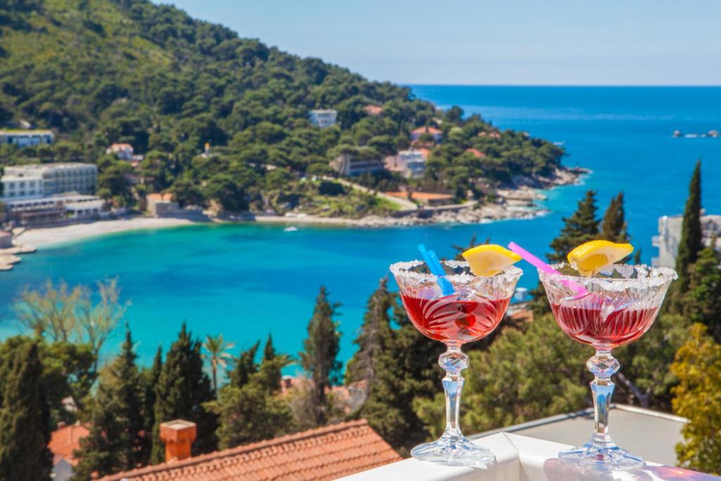 dos copas de vino sentadas en una cornisa con vistas a la playa en Cosmopolitan House Dubrovnik, en Dubrovnik