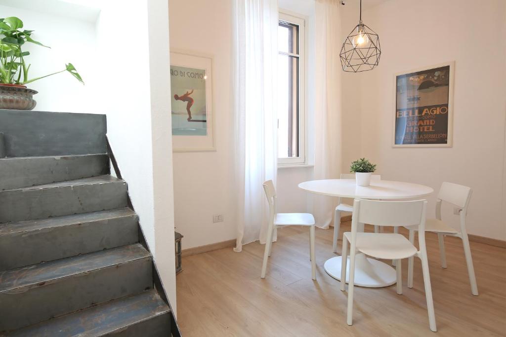 Habitación con mesa, sillas y escalera. en palazzo barindelli suite bianca en Bellagio