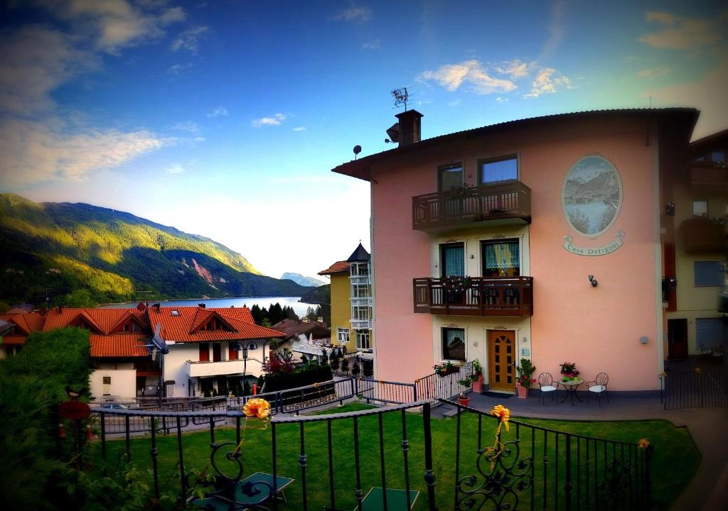 ein großes rosafarbenes Gebäude mit Balkon darüber in der Unterkunft Casa Vacanze Dorigoni in Molveno