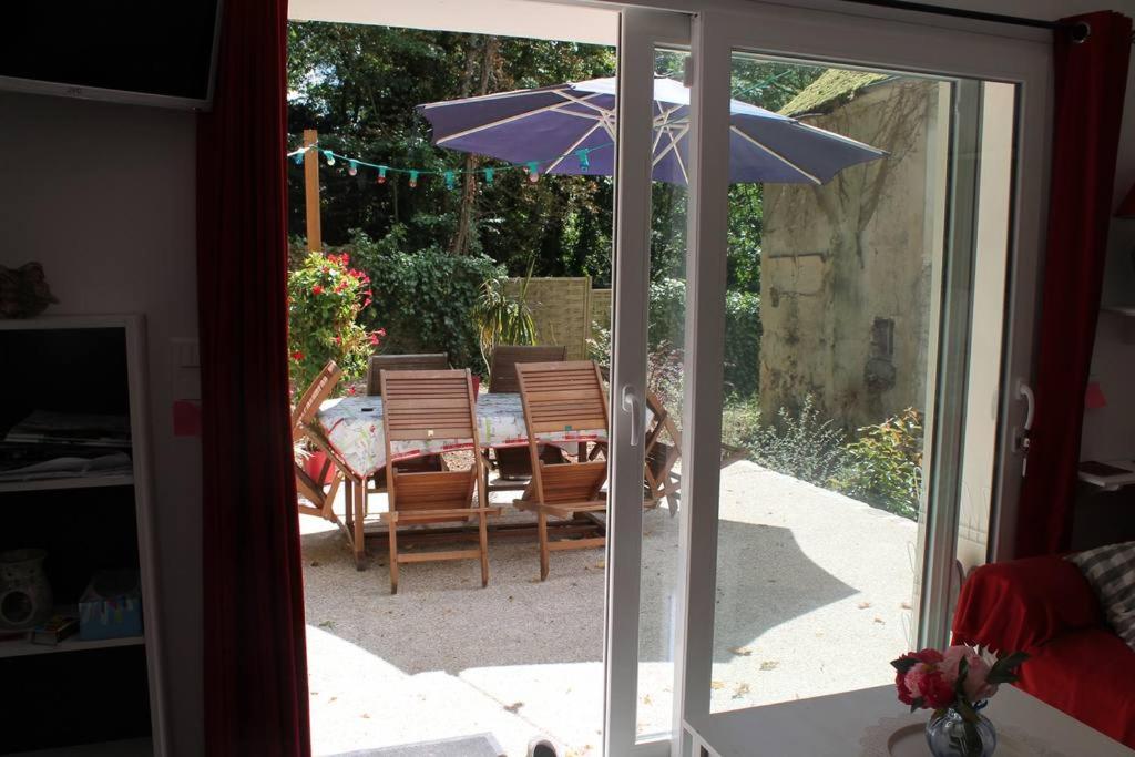 an open door to a patio with a table and an umbrella at Birchbank Cottage in Coulommiers