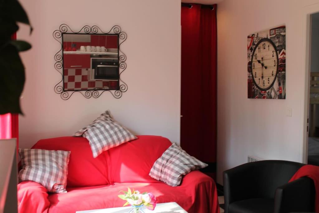 a red couch in a room with a clock on the wall at Birchbank Cottage in Coulommiers