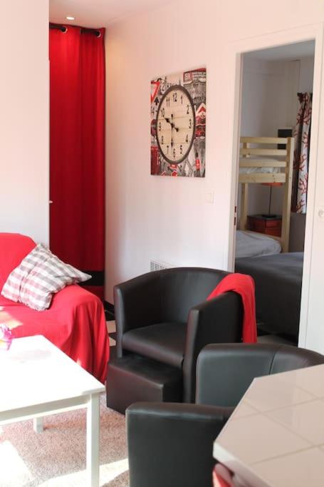 a living room with a couch and a clock on the wall at Birchbank Cottage in Coulommiers