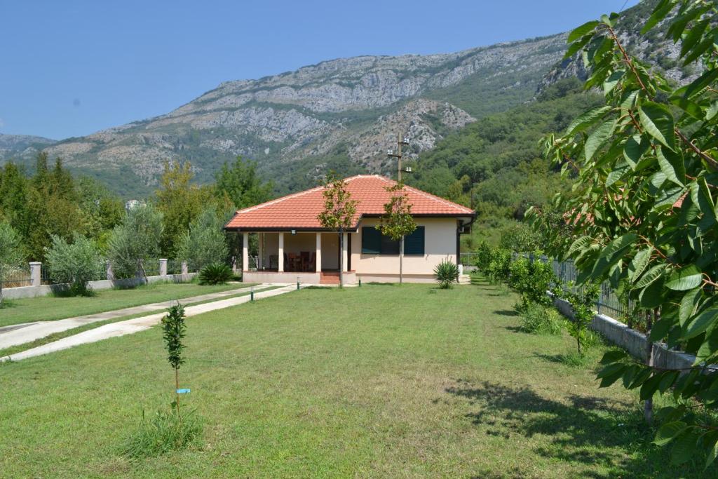 a house with a garden and mountains in the background at Guest House Radulovic in Petrovac na Moru
