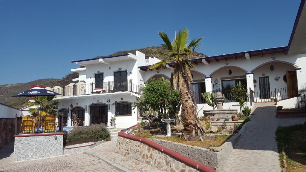 a white house with a palm tree in front of it at La Casona Azul Bed n Breakfast in Santa Rosa de Jáuregui