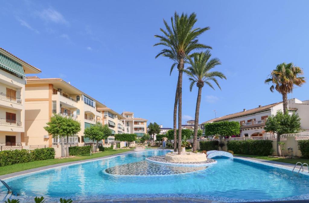 ラ・マタにあるBeach Apartment Torrevieja La Mata, Alicante Parque Mar 1のヤシの木と建物のあるスイミングプール