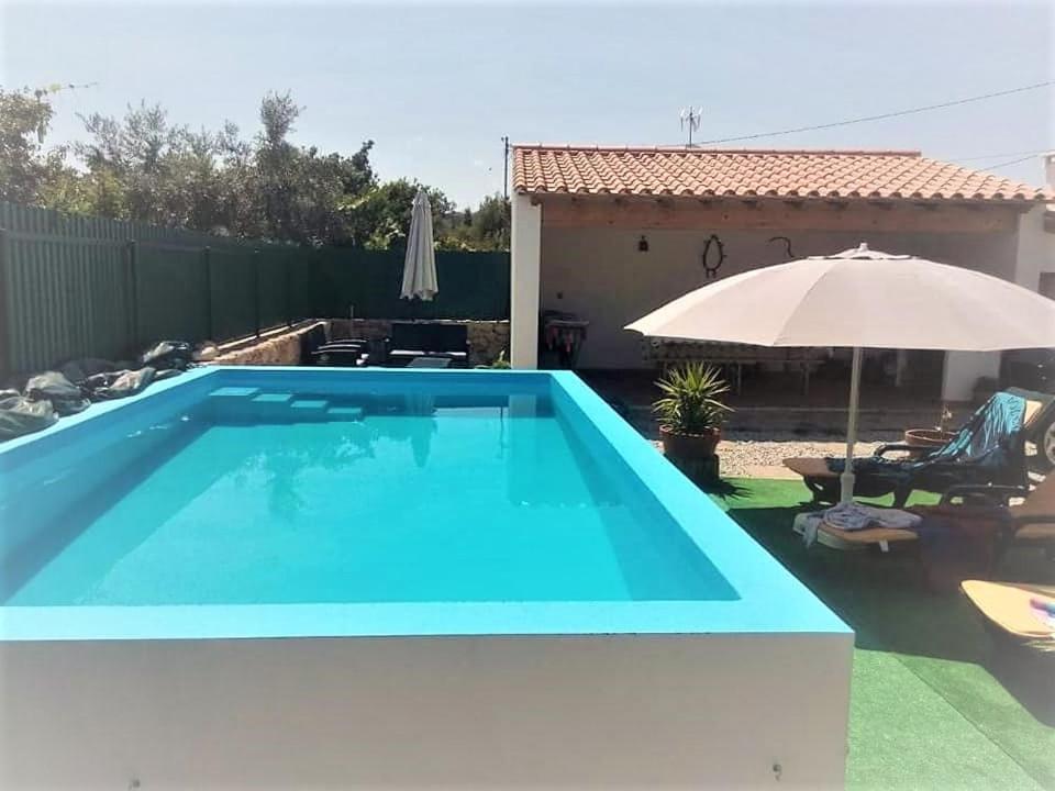 una piscina blu con ombrellone e una casa di Casas de Marvão - Casa do Ribeiro a Marvão