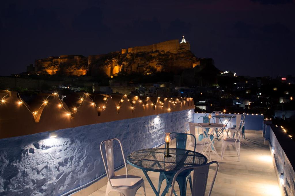 a table and chairs on a balcony at night with a castle at Jewel Palace Haweli in Jodhpur