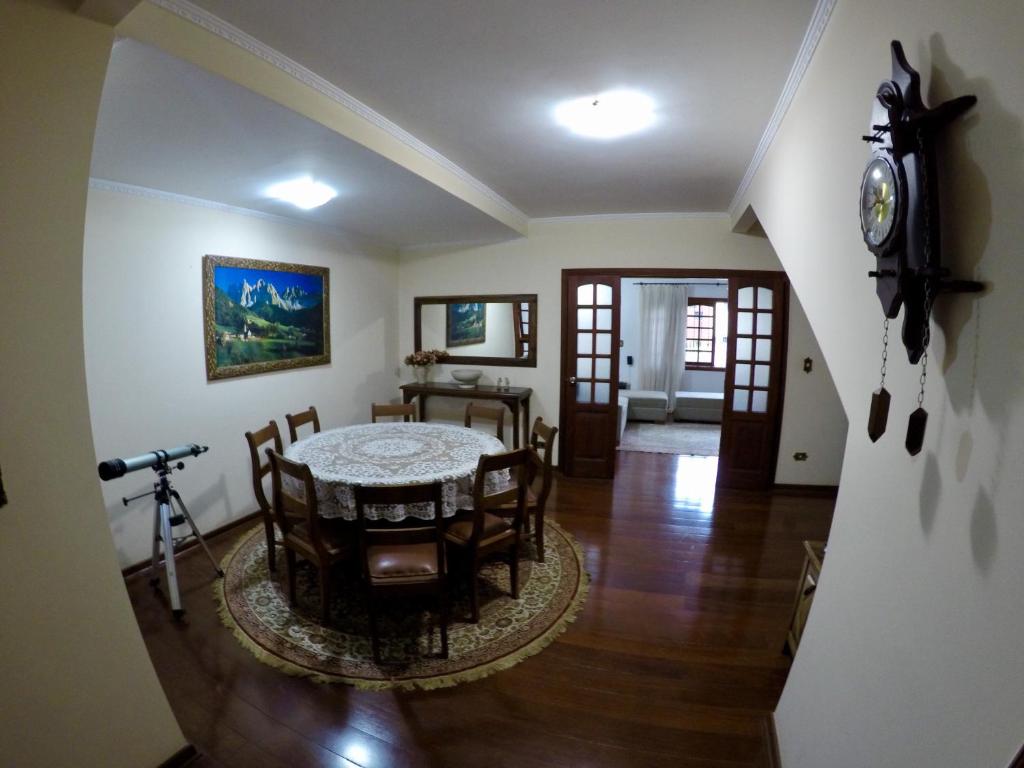 une salle à manger avec une table, des chaises et une horloge dans l'établissement Confortável casa de madeira, à Poços de Caldas