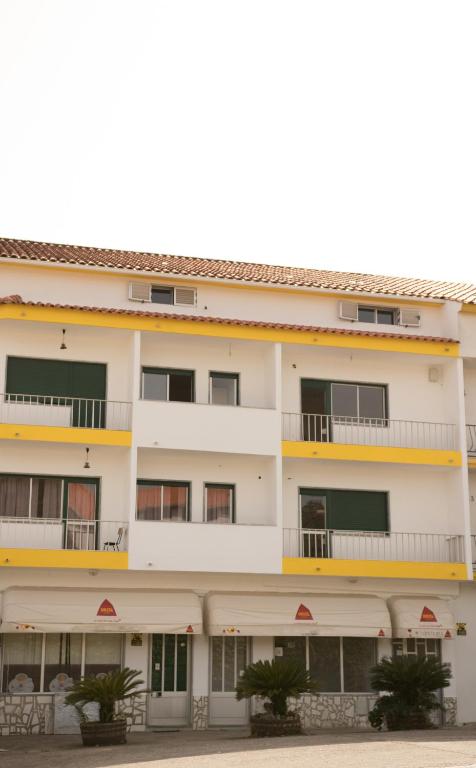 ein Wohnhaus mit Balkonen und Bäumen in der Unterkunft Suites Do Pinhal in Proença-a-Nova