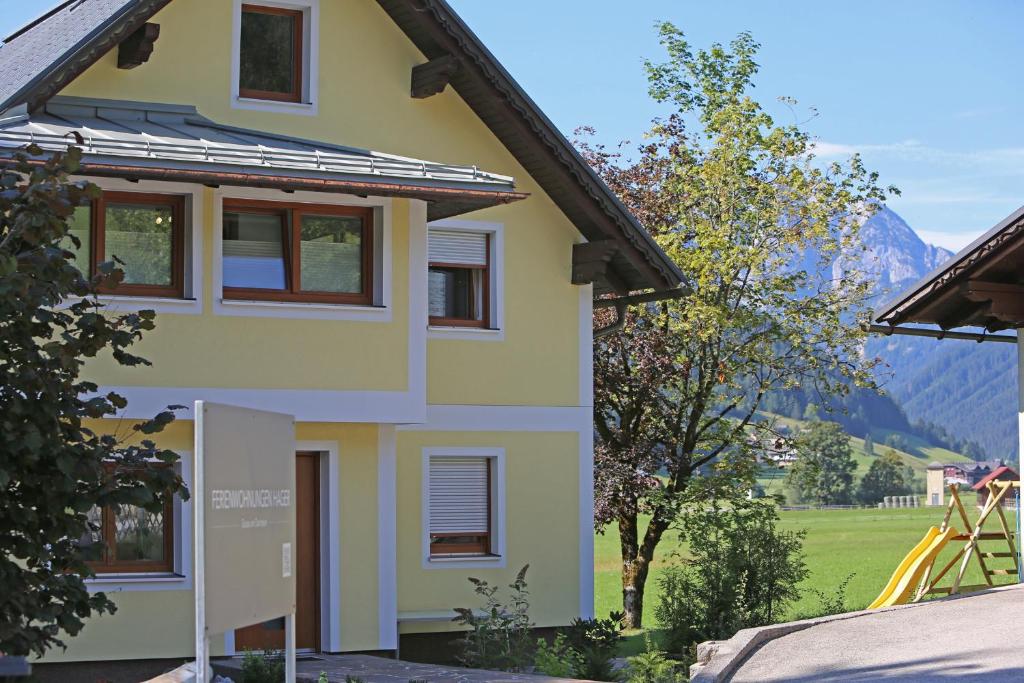 a yellow house with mountains in the background at Ferienwohnungen Hager in Gosau