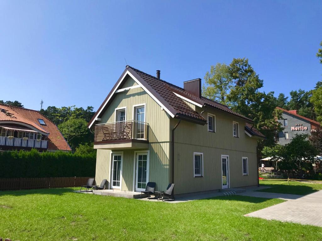 ein Haus mit Balkon auf einem Hof in der Unterkunft Apartment Amber White in Nida