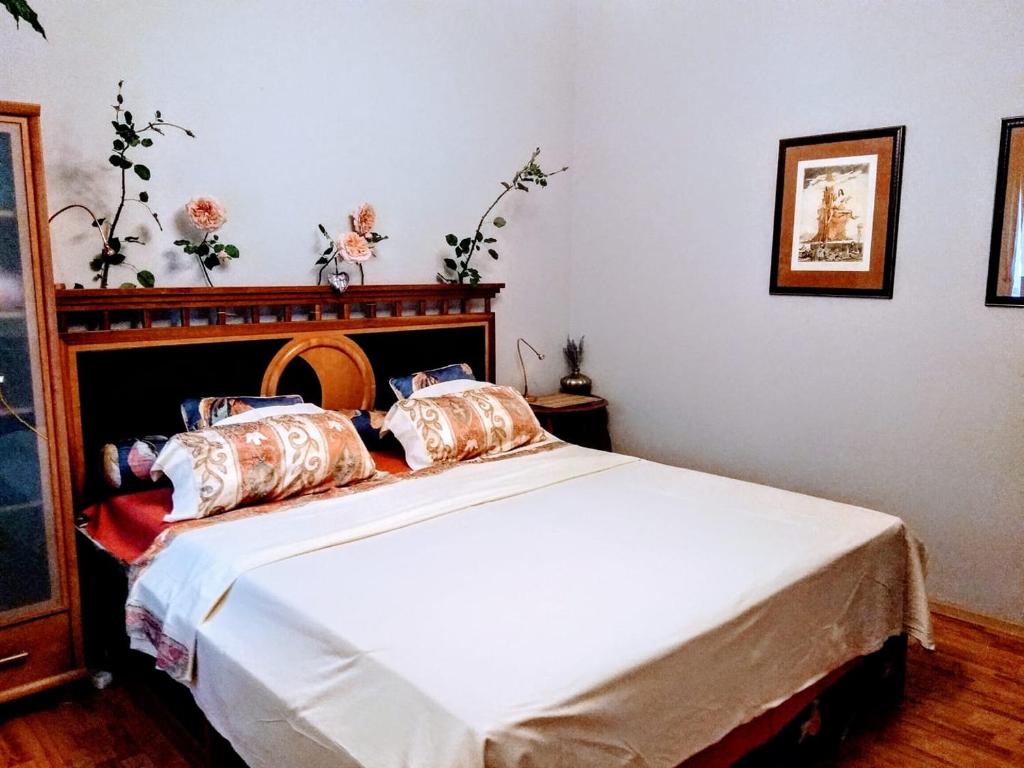 Schlafzimmer mit einem Bett mit weißer Bettwäsche und Kissen in der Unterkunft Villa Victoria in Mosonmagyaróvár