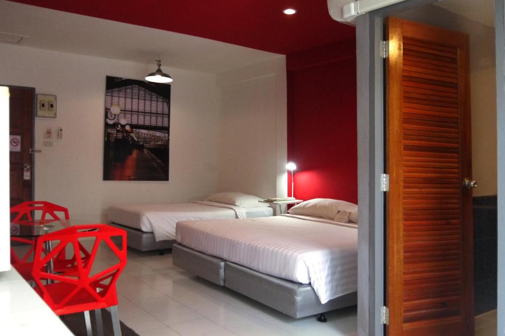 2 Betten in einem Zimmer mit roten Akzenten in der Unterkunft Sino @ Thungsong in Thung Song
