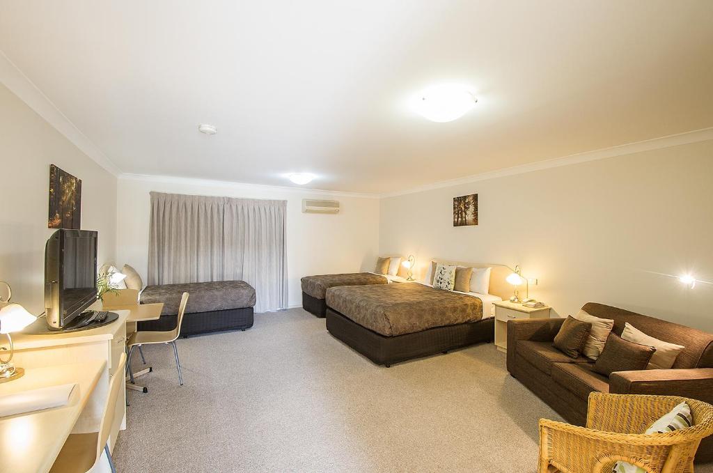 ein Hotelzimmer mit 2 Betten und einem Sofa in der Unterkunft Tuckerbox Motor Inn in Gundagai