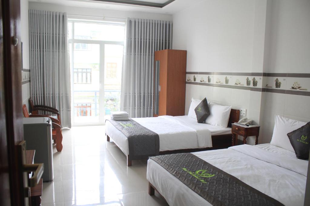 a hotel room with two beds and a window at Mai Tra Hotel in Quy Nhon