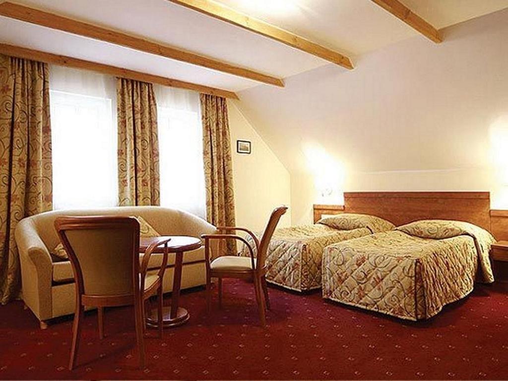 a hotel room with two beds and a table and chairs at Pensjonat M.F. in Elblag