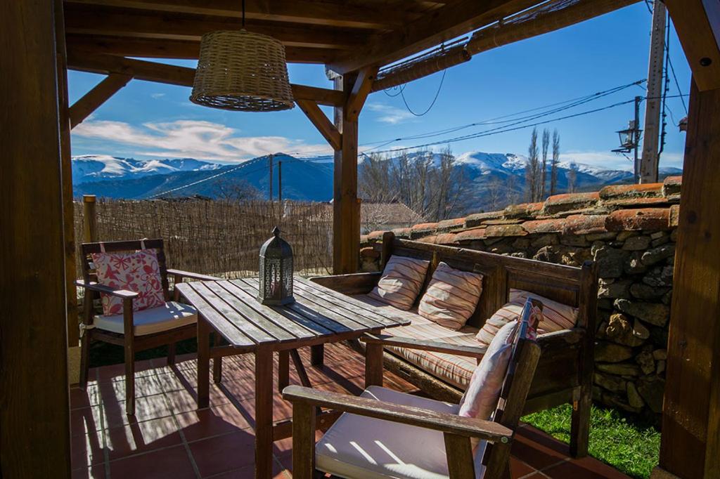 a wooden table and chairs on a patio with mountains at Casa rural La Rasa in Cabezas Altas