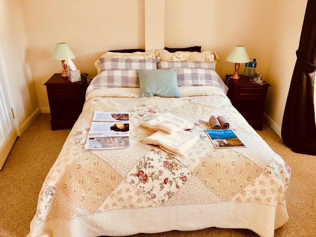 a bedroom with a bed with a blanket and books at Treasure Box Retreat in Clifden