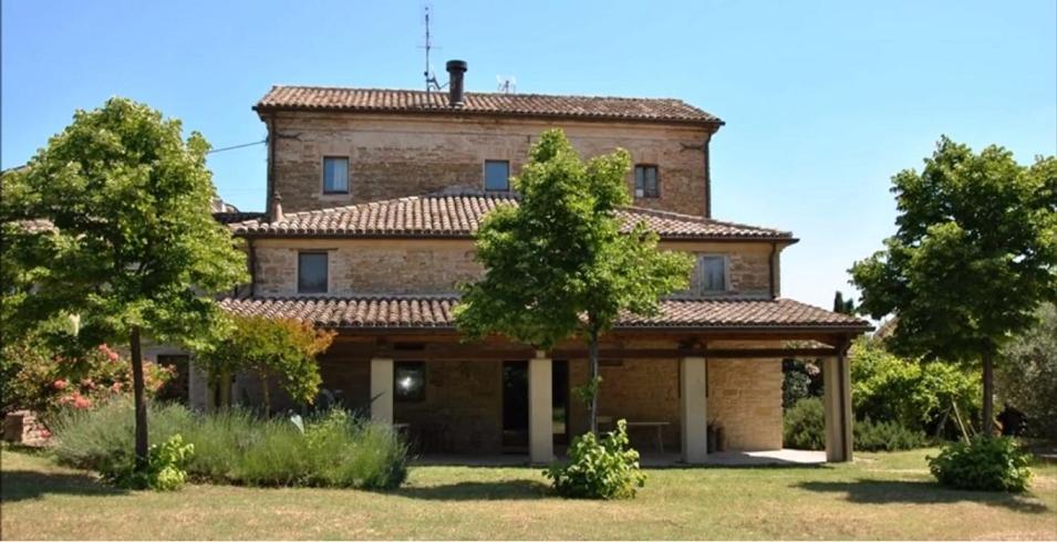 una gran casa de ladrillo con árboles delante de ella en Stone farmhouse in Moie, en Moie