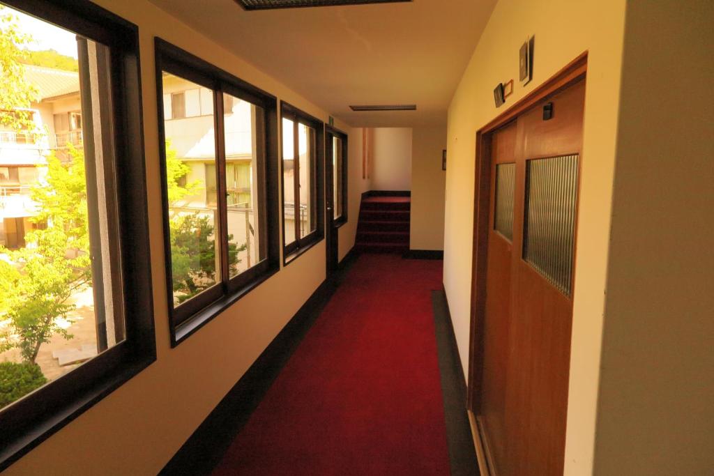 a hallway with windows and a red carpet at OkutsuHotSpa IkedayaKajikaen in Kagamino