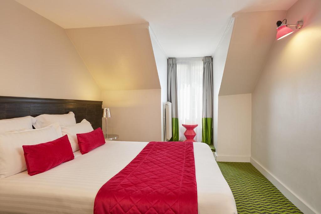 a bedroom with a large bed with red pillows at Hotel Antin Trinité in Paris
