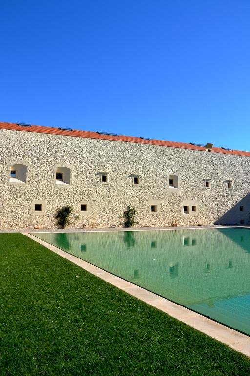 a building with a swimming pool in the grass at Bernardas Convent Apartment in Tavira