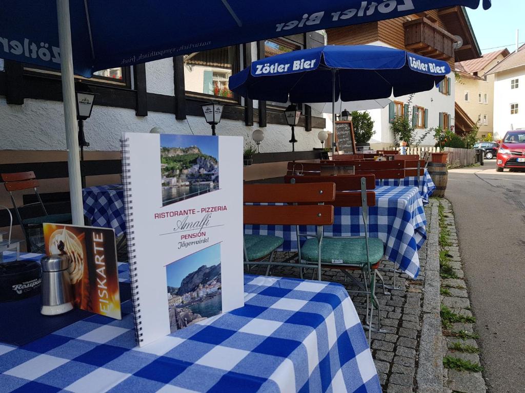 une table bleue et blanche avec des chaises et un parasol dans l'établissement Pension – Restaurant Jägerwinkl, à Rettenberg