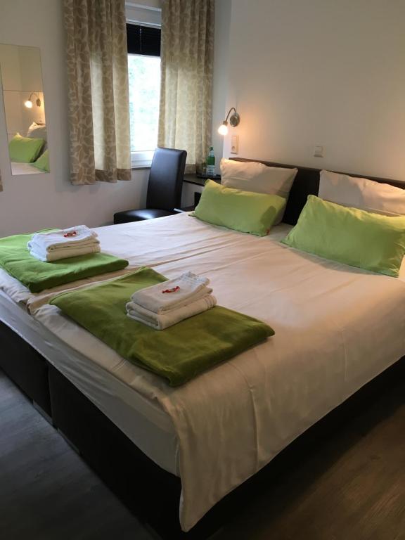 un grande letto con asciugamani verdi sopra di Hotel Tau-Lünne a Haselünne