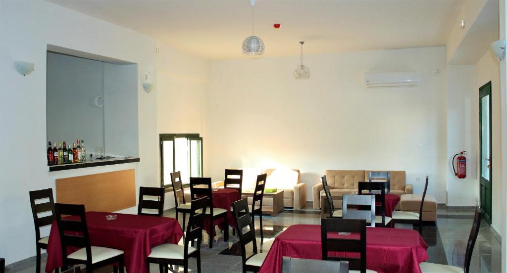 uma sala de jantar com mesas e cadeiras com toalha de mesa vermelha em chalkiotis hotel em Anaxos