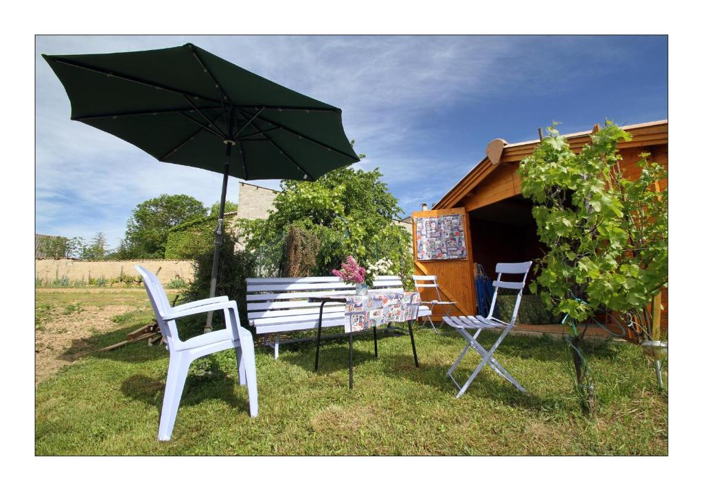 una mesa con sillas y una sombrilla en el césped en gîte la grange en Sainte-Croix