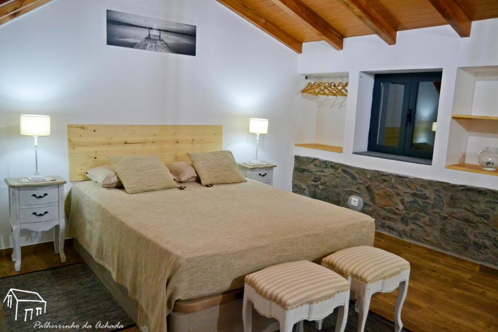 a bedroom with a large bed with two tables and two chairs at Palheirinho da Achada in Arco da Calheta
