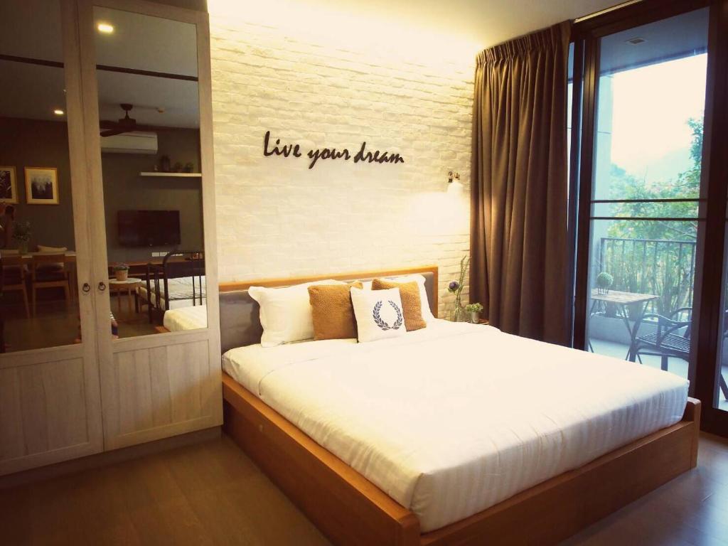 Live Your Dream Khaoyai في Phayayen: غرفة نوم مع سرير مع علامة على الحائط